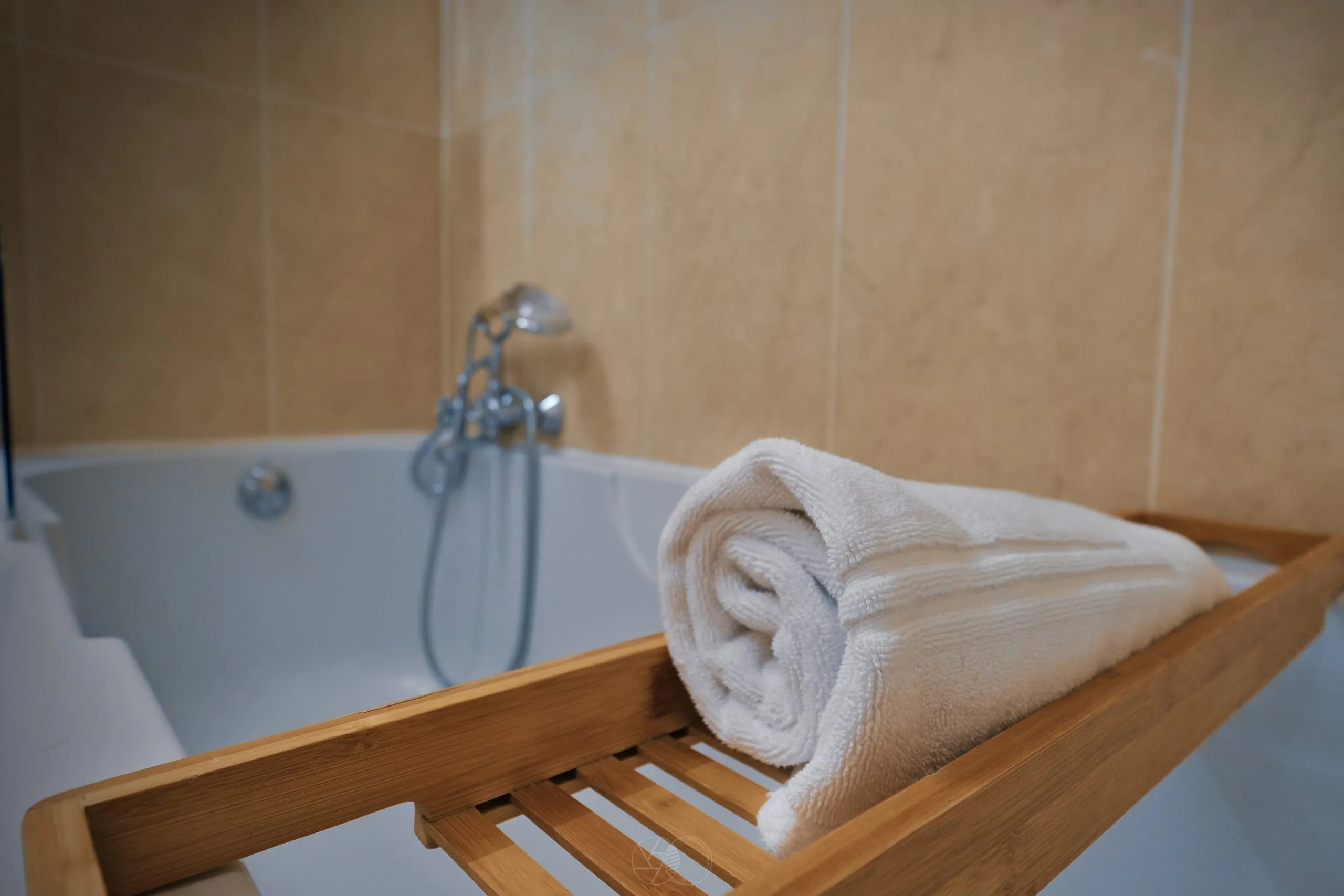 Baignoire de la chambre Vinalia avec plateau en bois et serviettes blanches pliées.