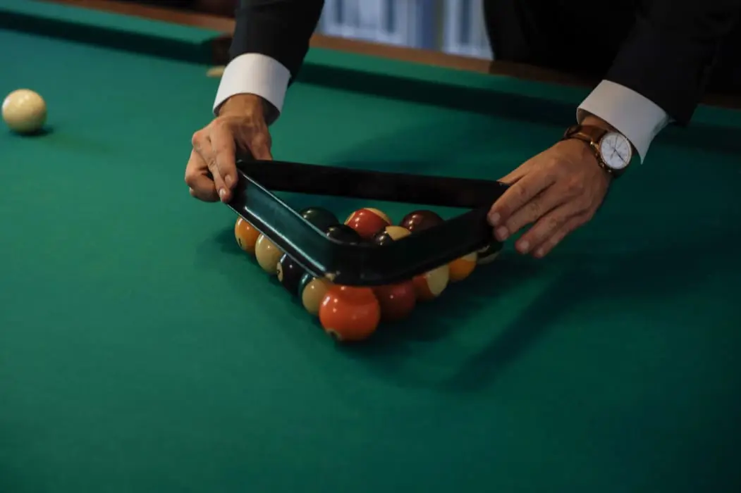 Joueur plaçant les boules sur le billard au tapis vert du Clos de Meyre.