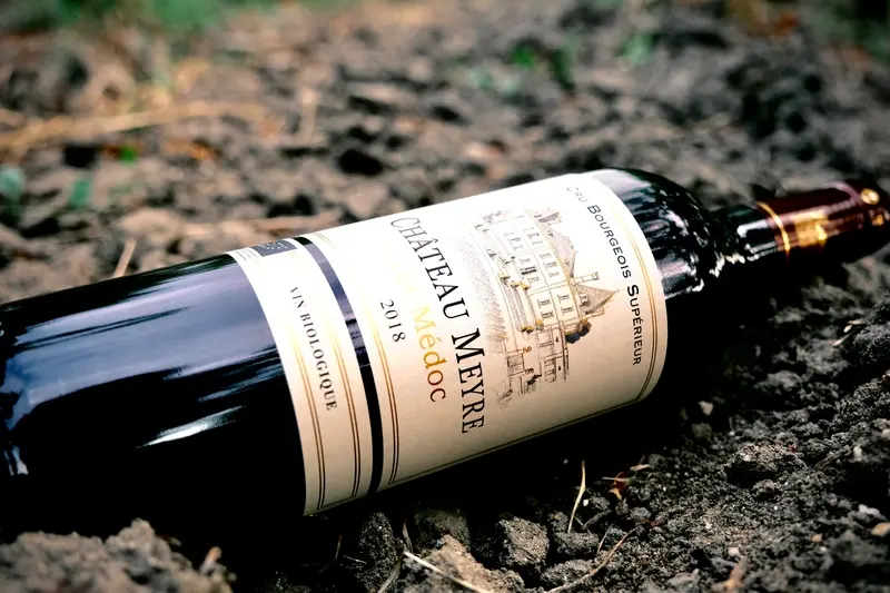 Bouteille de Château Meyre 2018 Haut-Médoc posée sur le sol du vignoble.