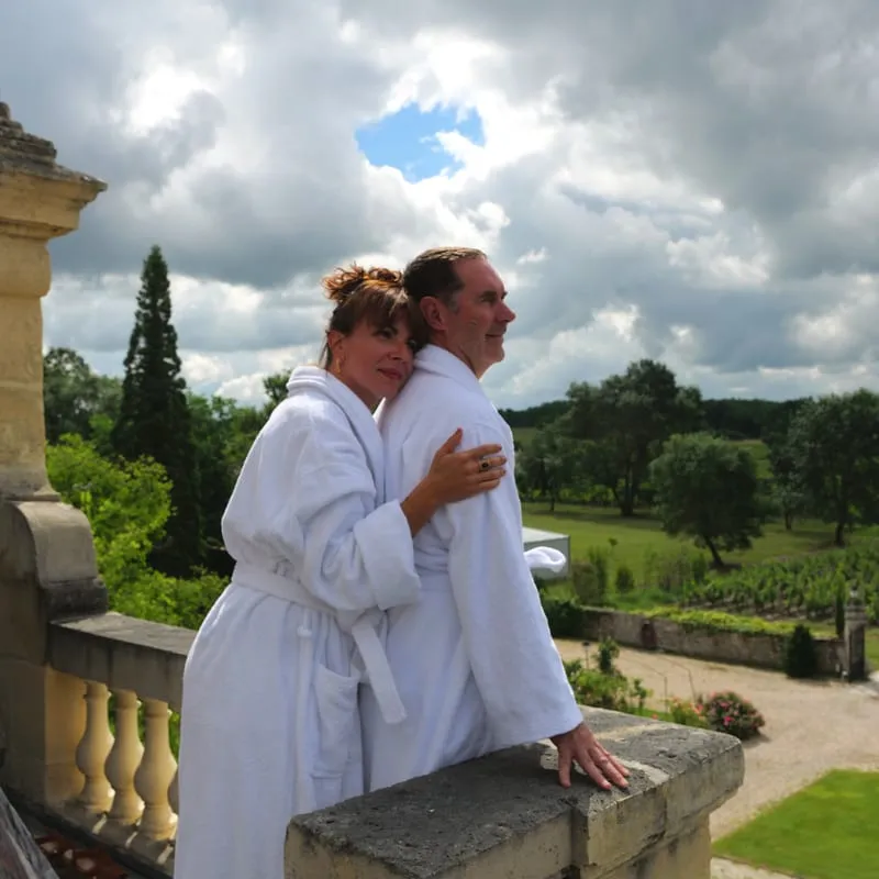 Couple en peignoirs blancs sur une terrasse face au parc du Clos de Meyre.